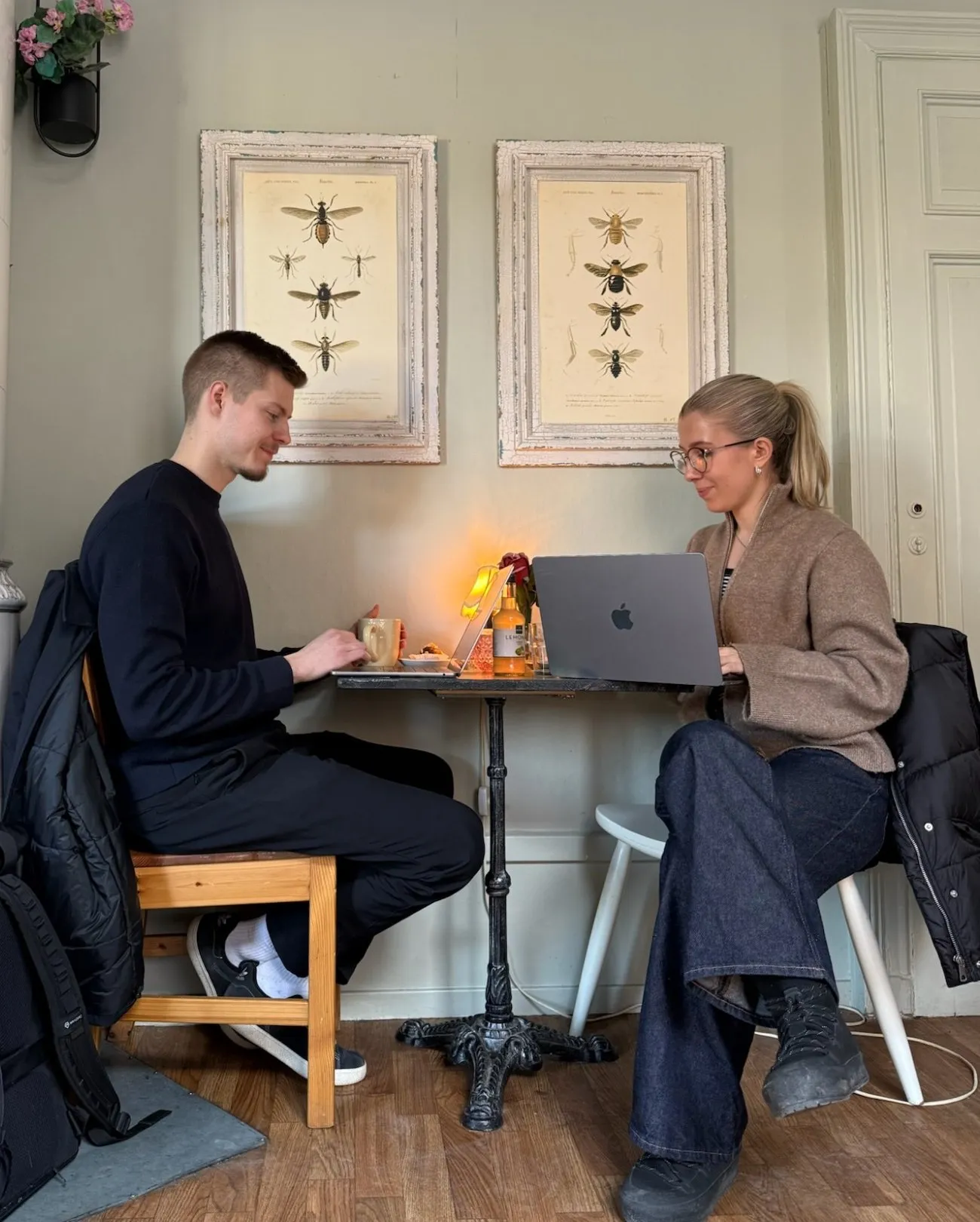 Max och Kajsa jobbar vid ett kafébord, med kaffe och varsin dator